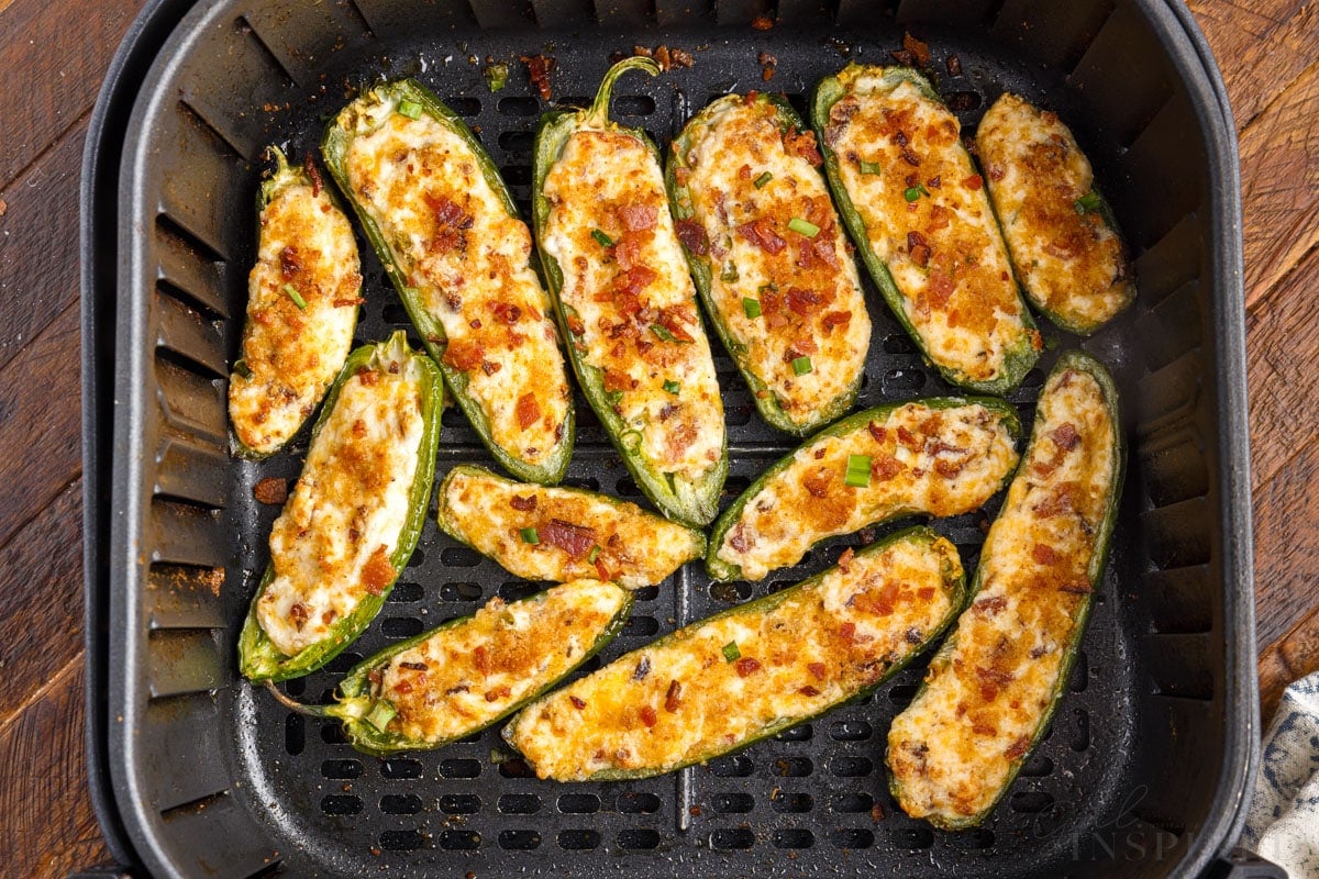 close up of cooked stuffed jalapenos in air fryer basket
