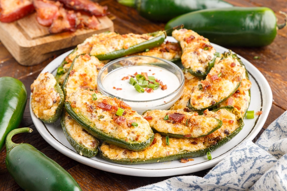a plate of air fryer jalapeno poppers stacked on each other with ranch dressing in a small dish in the center