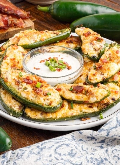 front view of a plate of air fryer stuffed jalapeno poppers with ranch dressing in a dish in the center