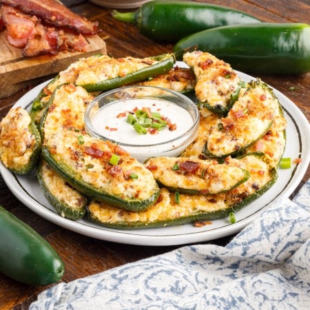 front view of a plate of air fryer stuffed jalapeno poppers with ranch dressing in a dish in the center