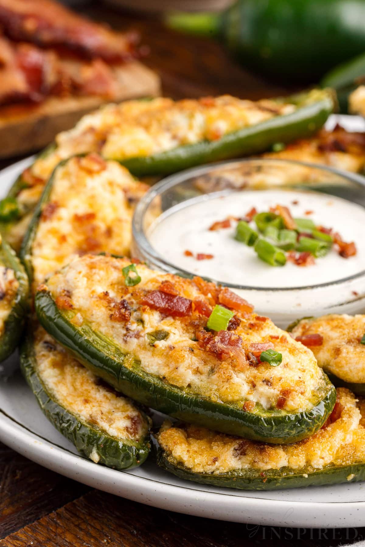 front view of a plate of stacked air fryer jalapeno poppers with ranch in the middle