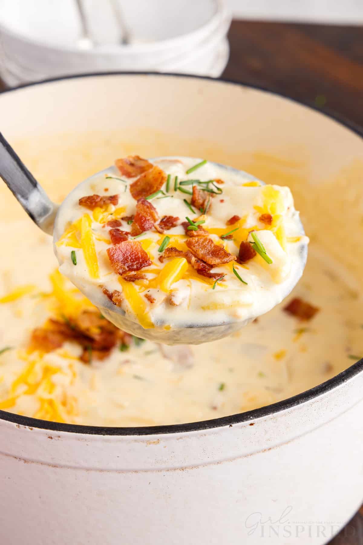 front view of a ladle full of bacon cheddar potato soup