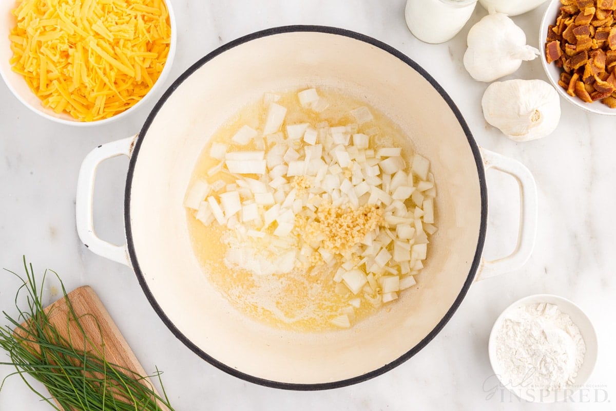 onions and garlic added to melted butter in dutch oven next to additional ingredients needed to make bacon cheddar potato soup