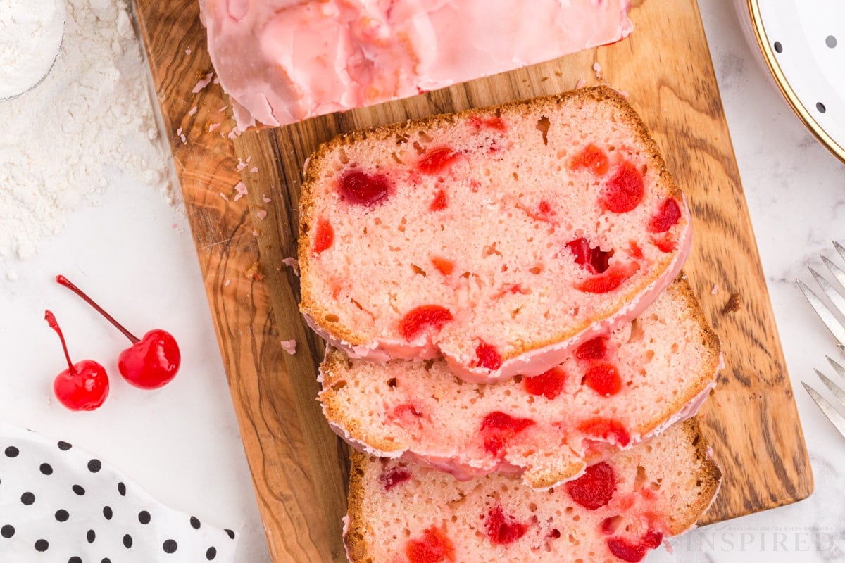 top close up of a cutting board with a loaf of cherry bread cut in to slices