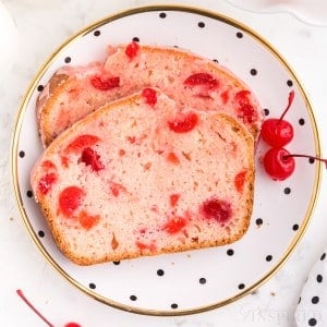 decorate plate with two slices of cherry bread stacked on top of each other with two cherries next to it