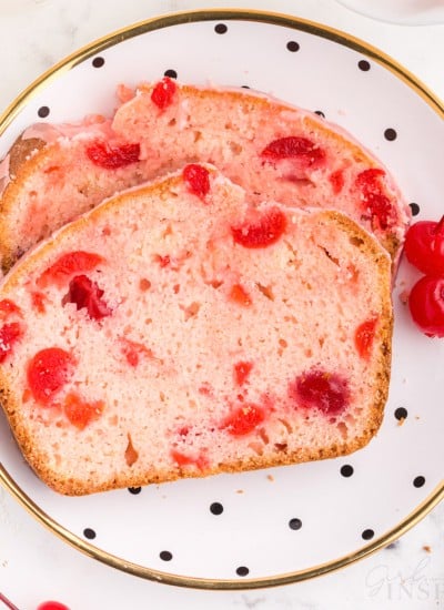 decorate plate with two slices of cherry bread stacked on top of each other with two cherries next to it