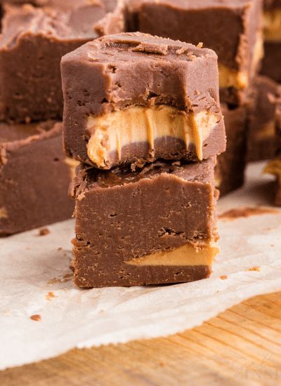 Sliced 2 ingredient chocolate peanut butter fudge on a parchment paper-lined wooden kitchen board