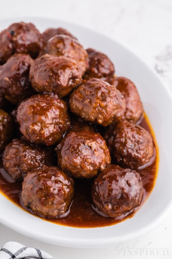 oval platter of crockpot meatballs with grape jelly and chili