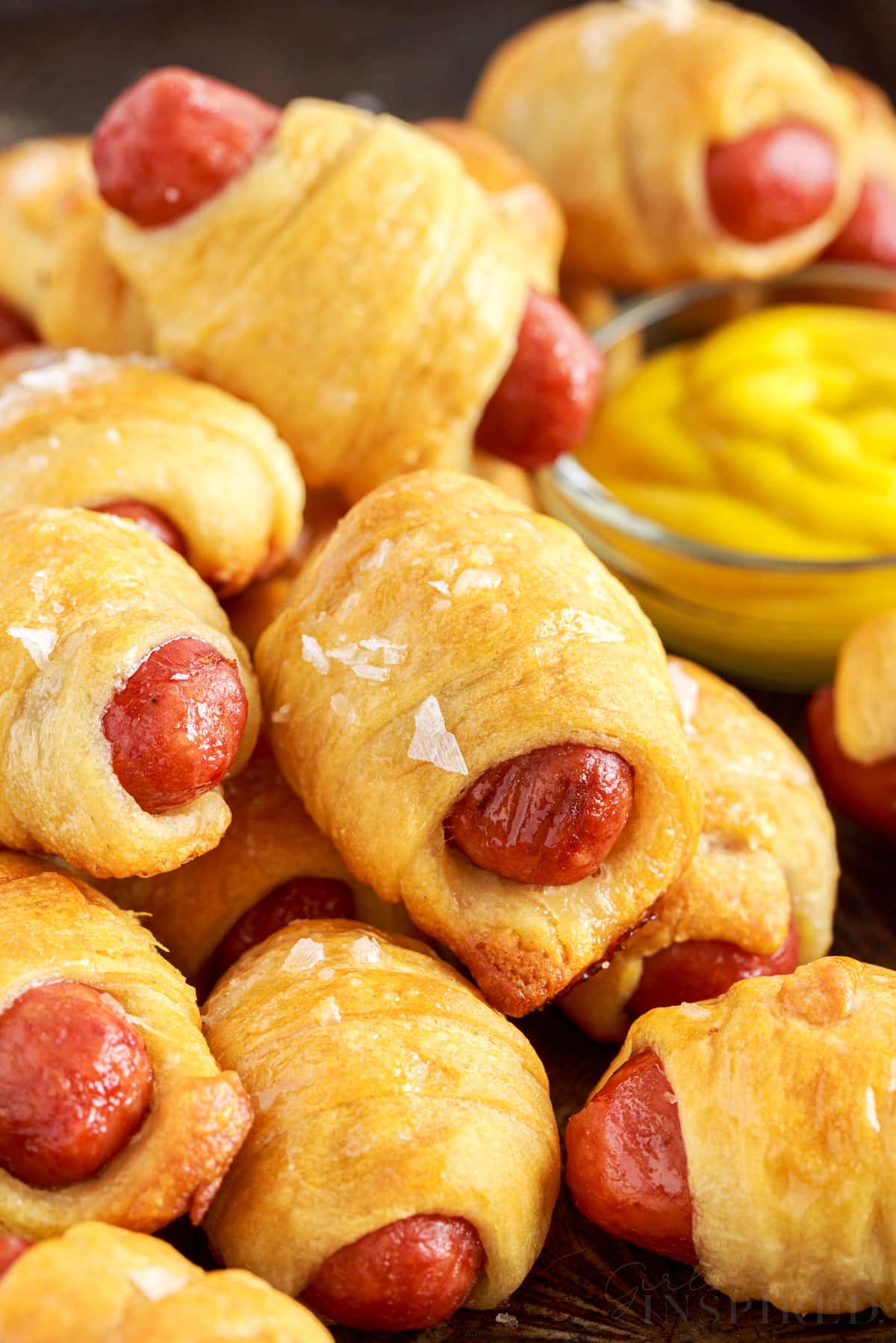stacked lil smokies pigs in a blanket with a small dish of mustard