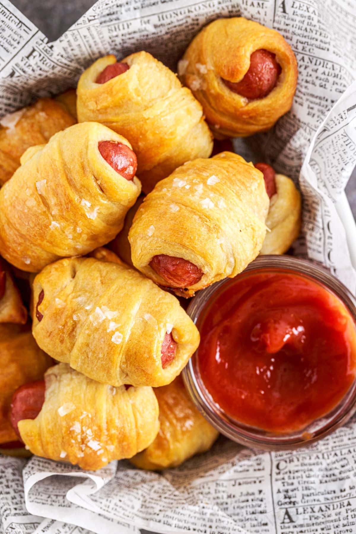 paper lined basket of lil smokies pigs in a blanket with a small dish of ketchup