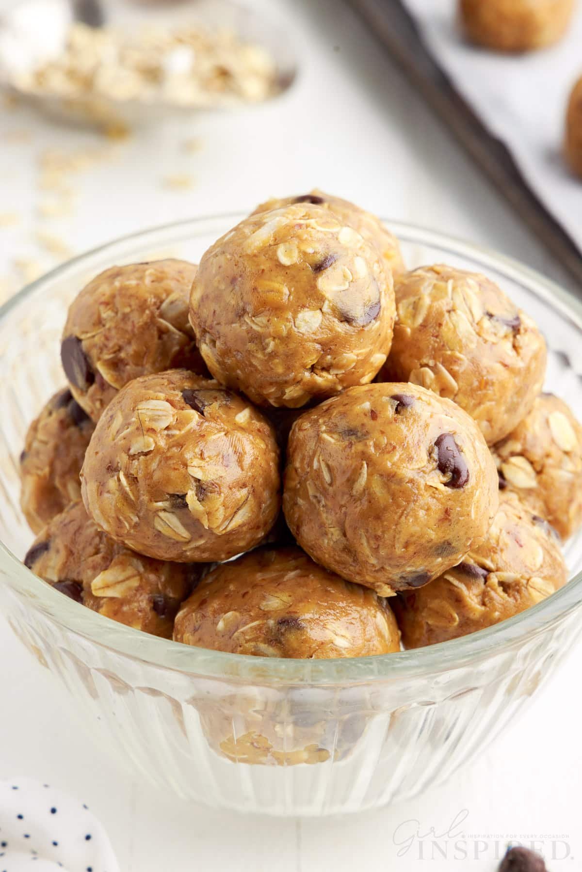 Bowl of peanut butter oat balls stacked in a small glass bowl.