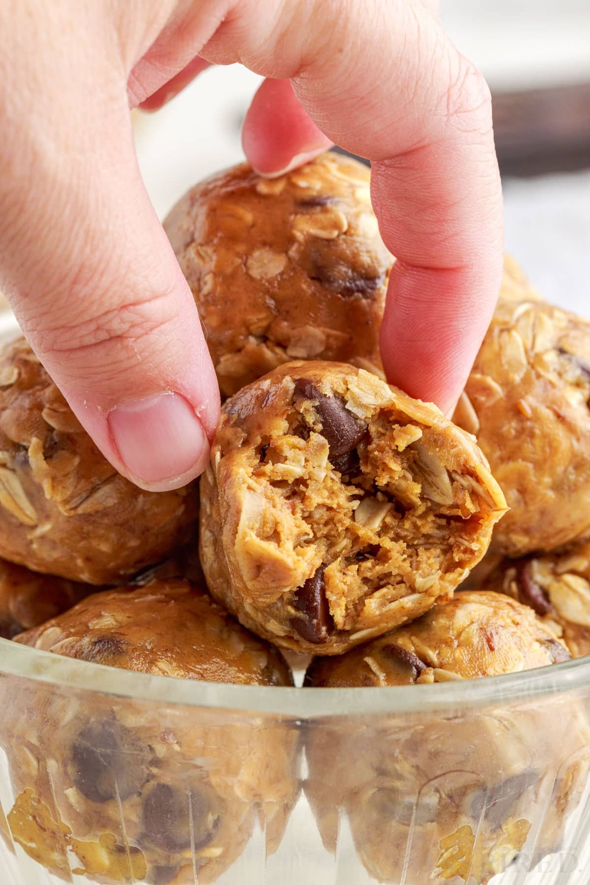 close up of no bake energy balls with a bite taken from one