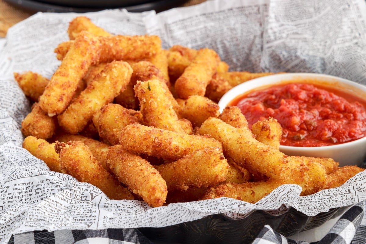 close up of stuffed ziti fritta in a lined basket with a small cup of sauce