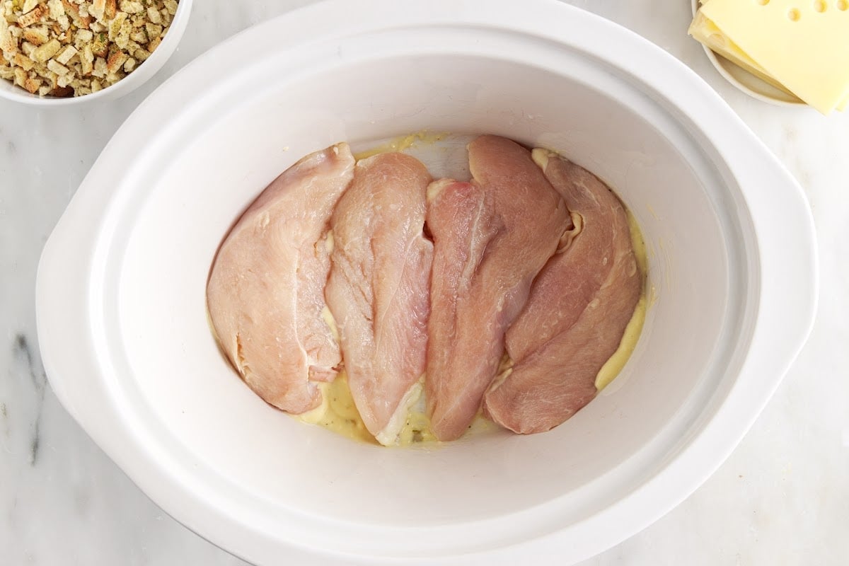 Chicken breasts layered in crockpot base.