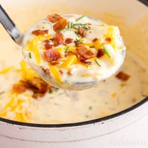 front view of a ladle full of bacon cheddar potato soup