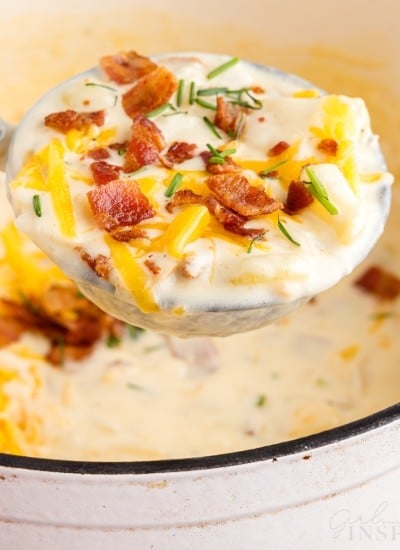 front view of a ladle full of bacon cheddar potato soup