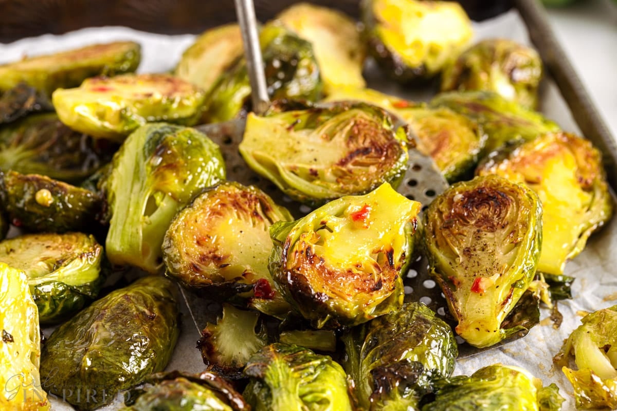 Close up of golden brown Brussels sprouts with sauce baked into them.