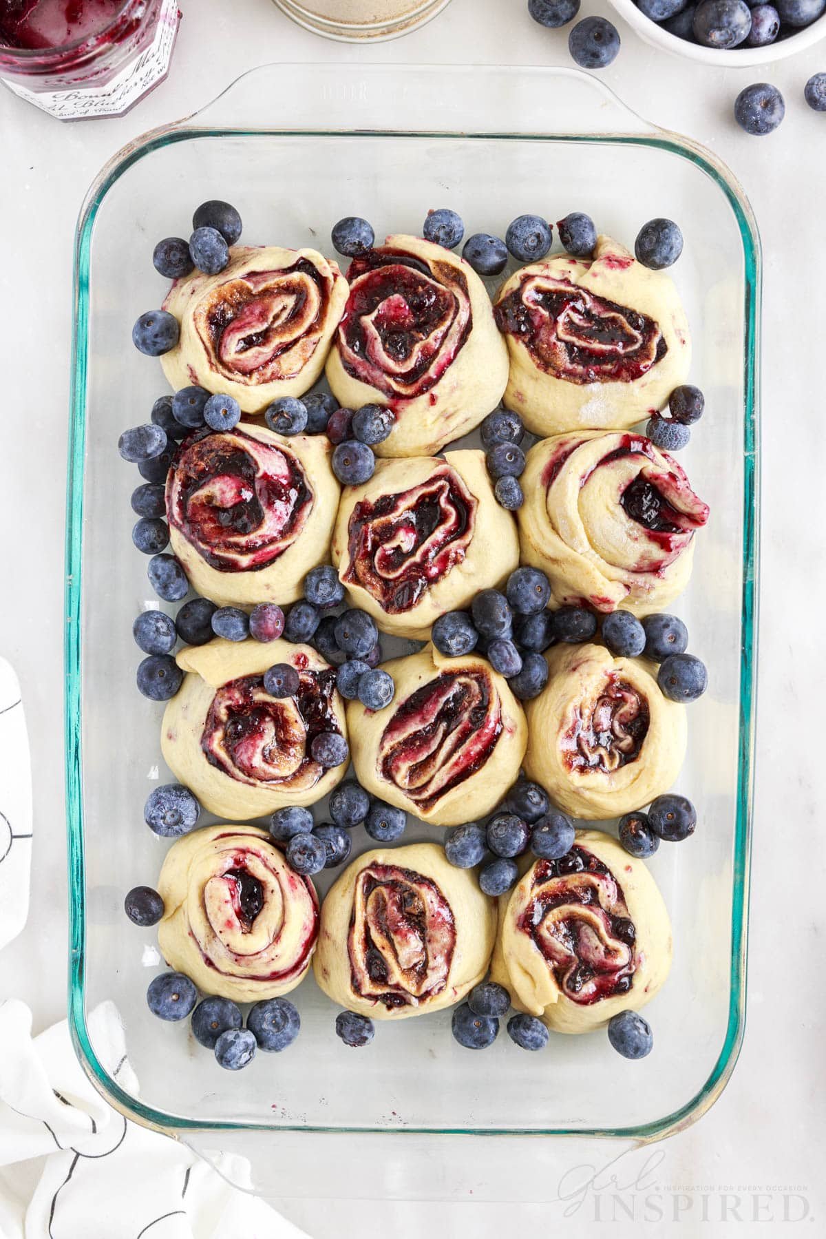 Blueberries placed around the cinnamon roll pieces in a 9x13.