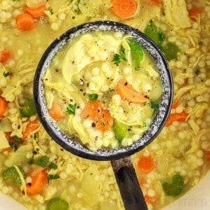 Top close up of a ladle full of chicken couscous soup.