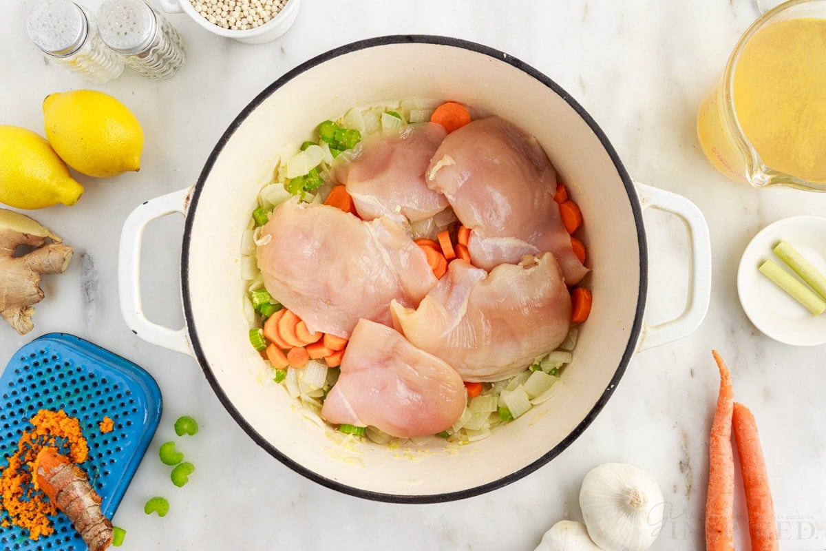 Chicken breasts added to dutch oven and veggies to make chicken couscous soup.