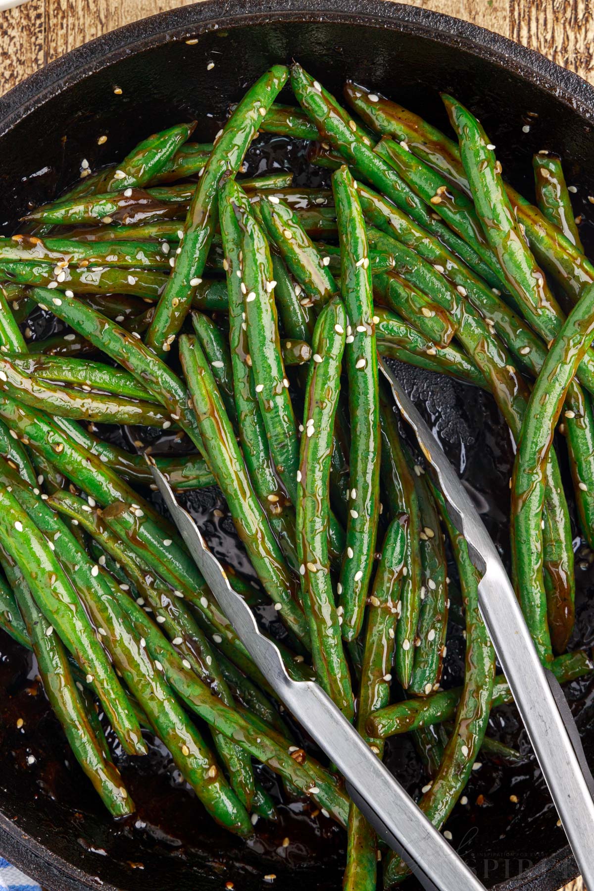 Tongs in a pan of Chinese buffet green beans.