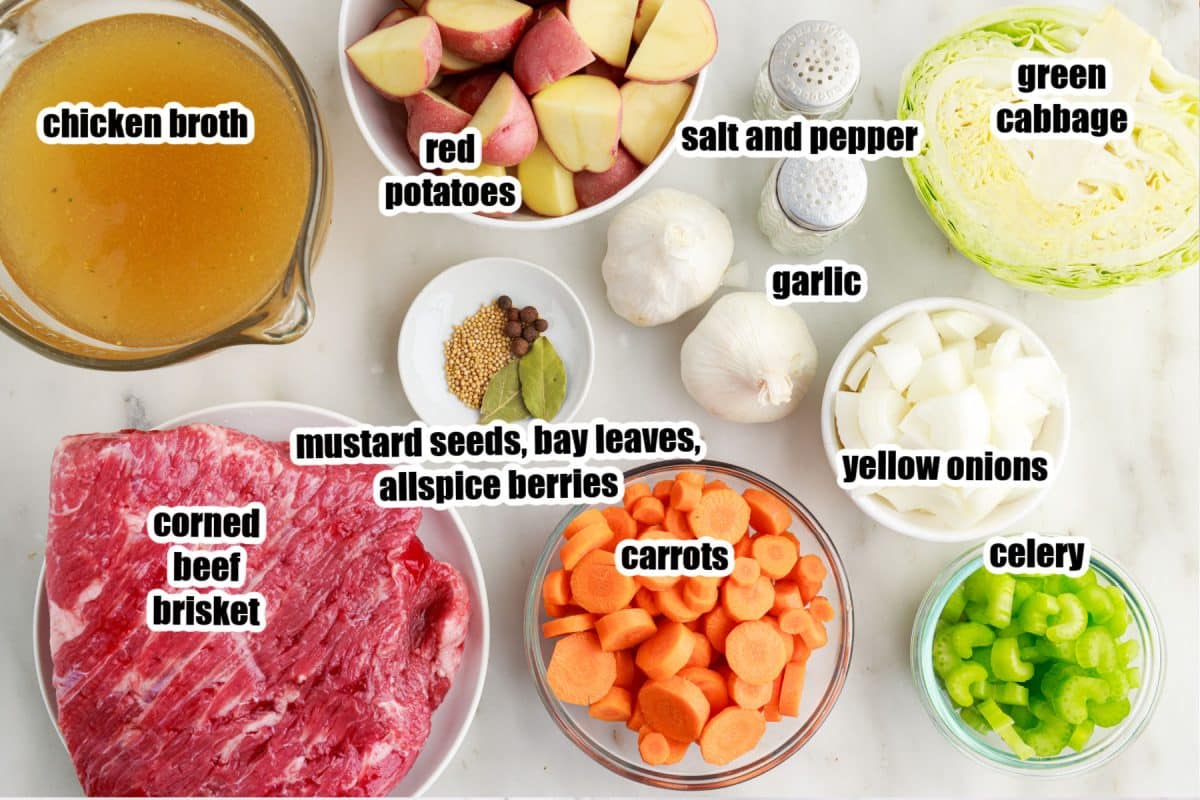 Individual ingredients set out for corned beef and cabbage soup, with text labels.