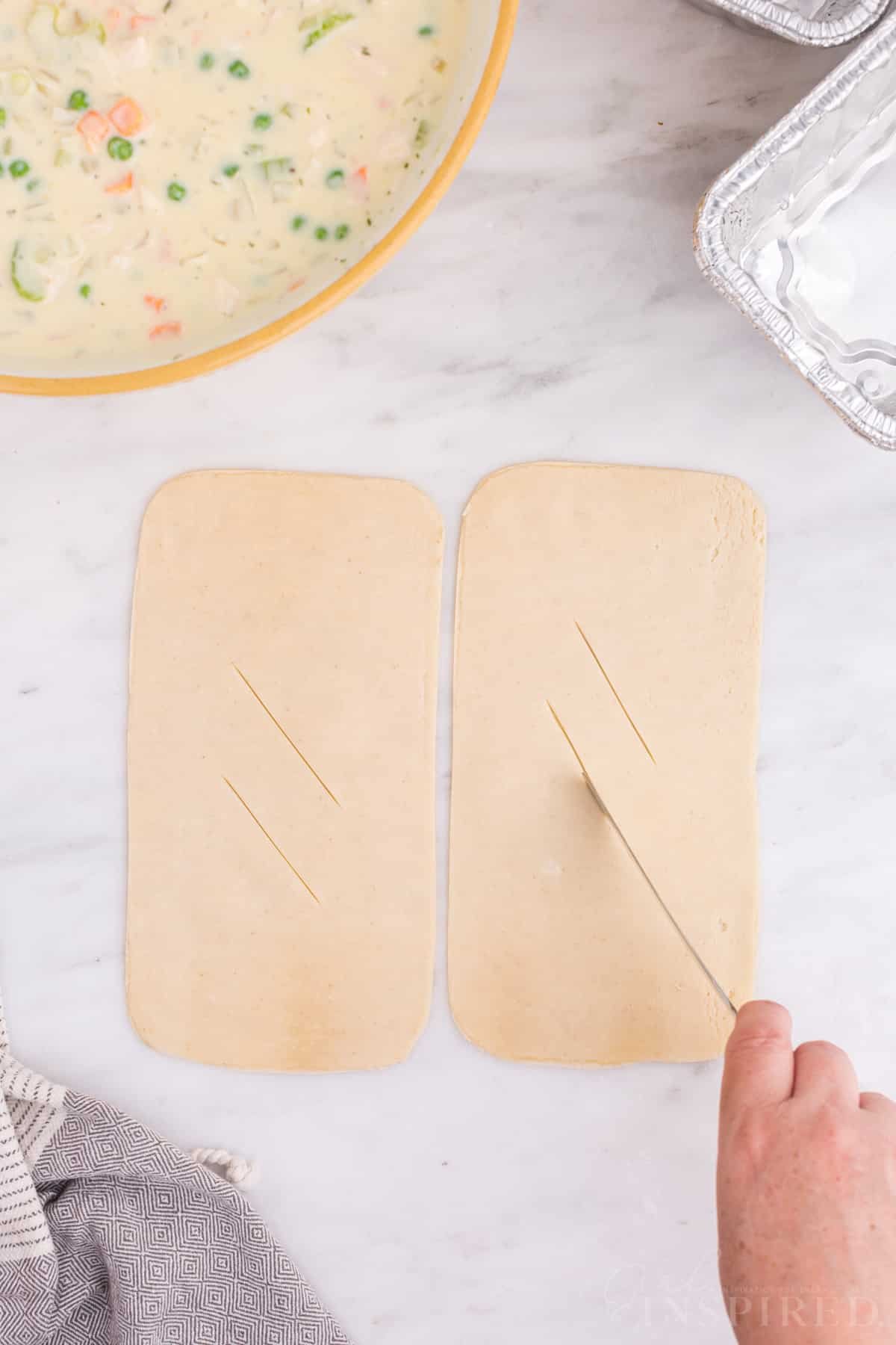 Cut out pie crust tops on a marble countertop, slits made in the crust tops for venting.