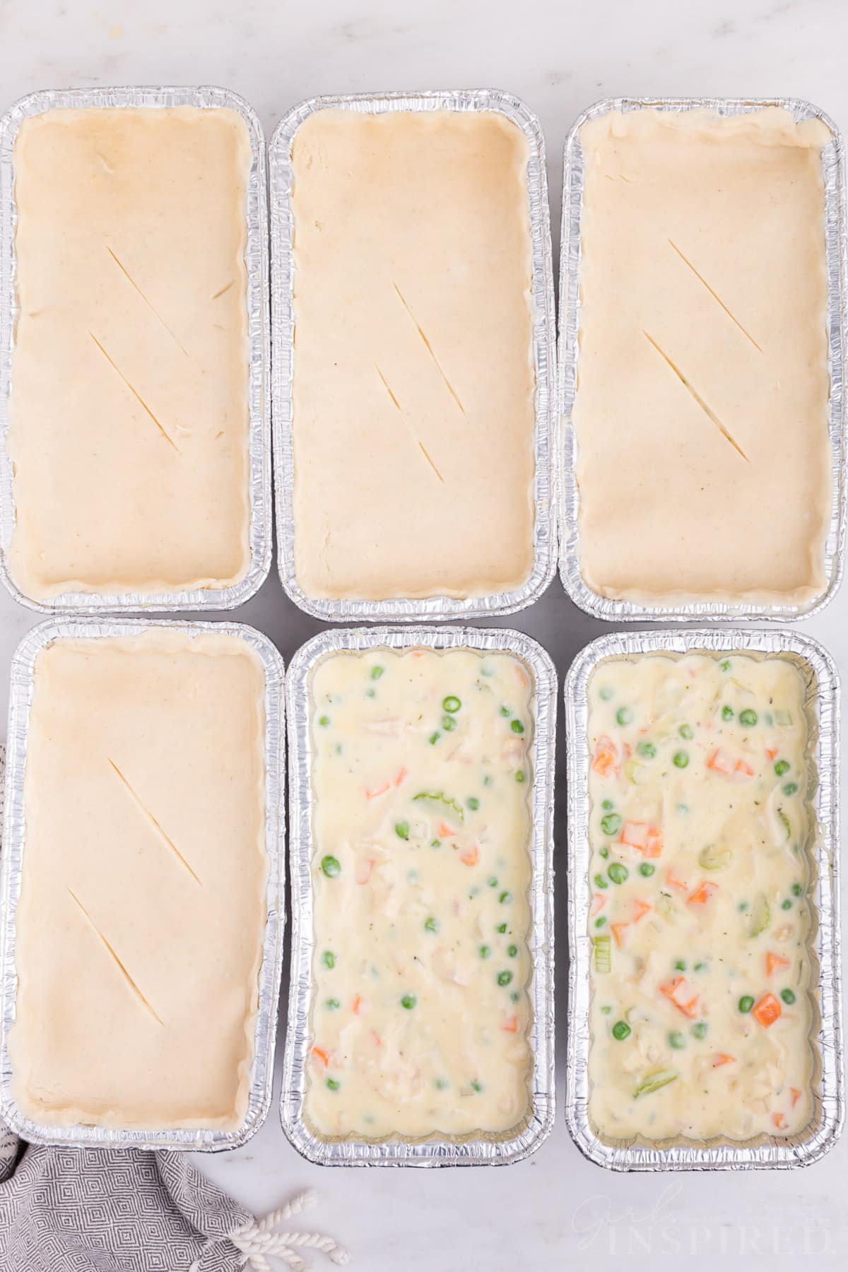 Six assembled Freezer Chicken Pot Pies with pie crust tops ready to be baked.