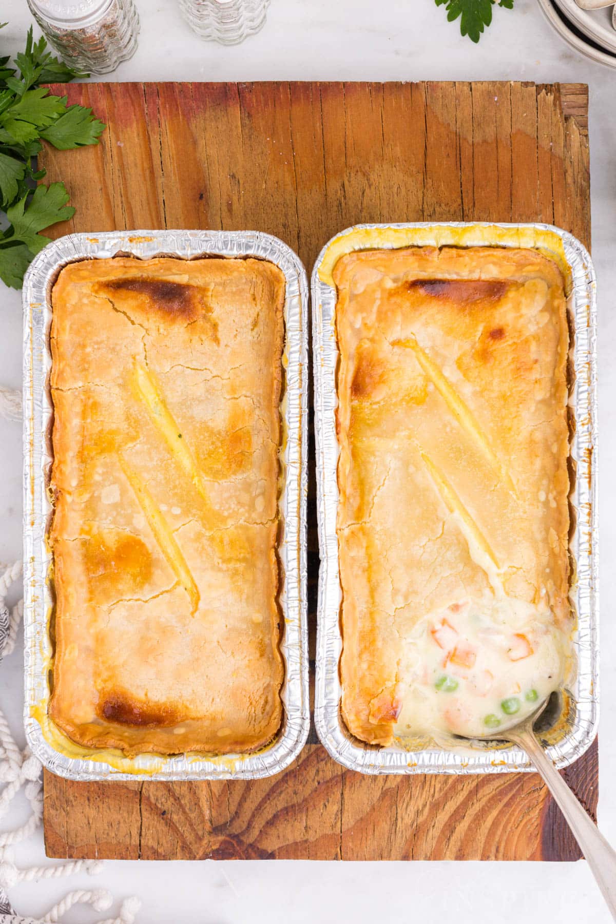 Two baked Freezer Chicken Pot Pies on a wooden kitchen board.