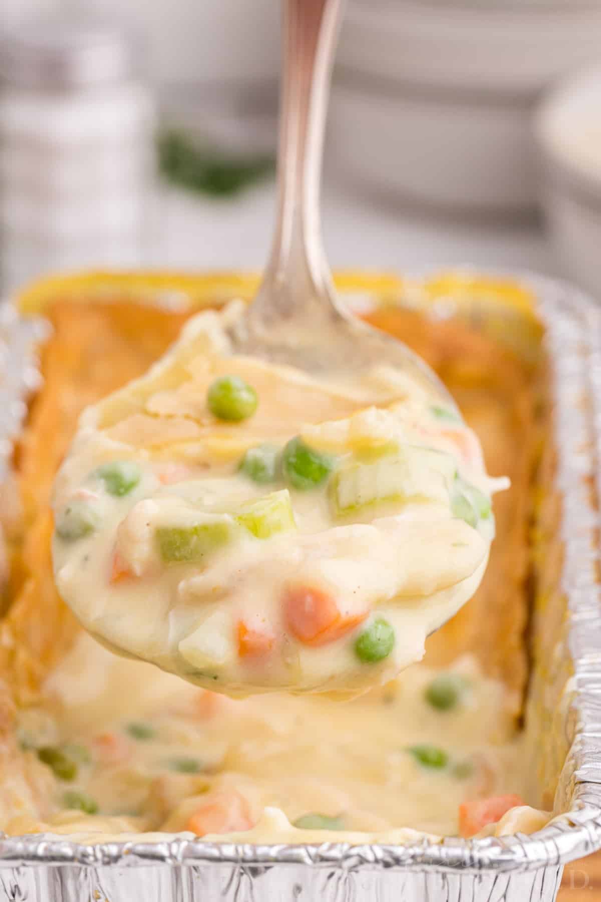 Close-up of Freezer Chicken Pot Pie with a helping of pie on a serving spoon held above the pie.