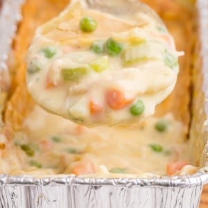 Close-up of Freezer Chicken Pot Pie with a helping of pie on a serving spoon held above the pot pie.