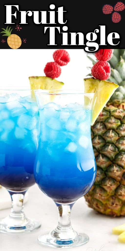 Close up of two tall glasses filled with fruit tingle cocktail and garnished with pineapple wedges and skewered raspberries, whole pineapple standing upright, pineapple garnish on a marble countertop.