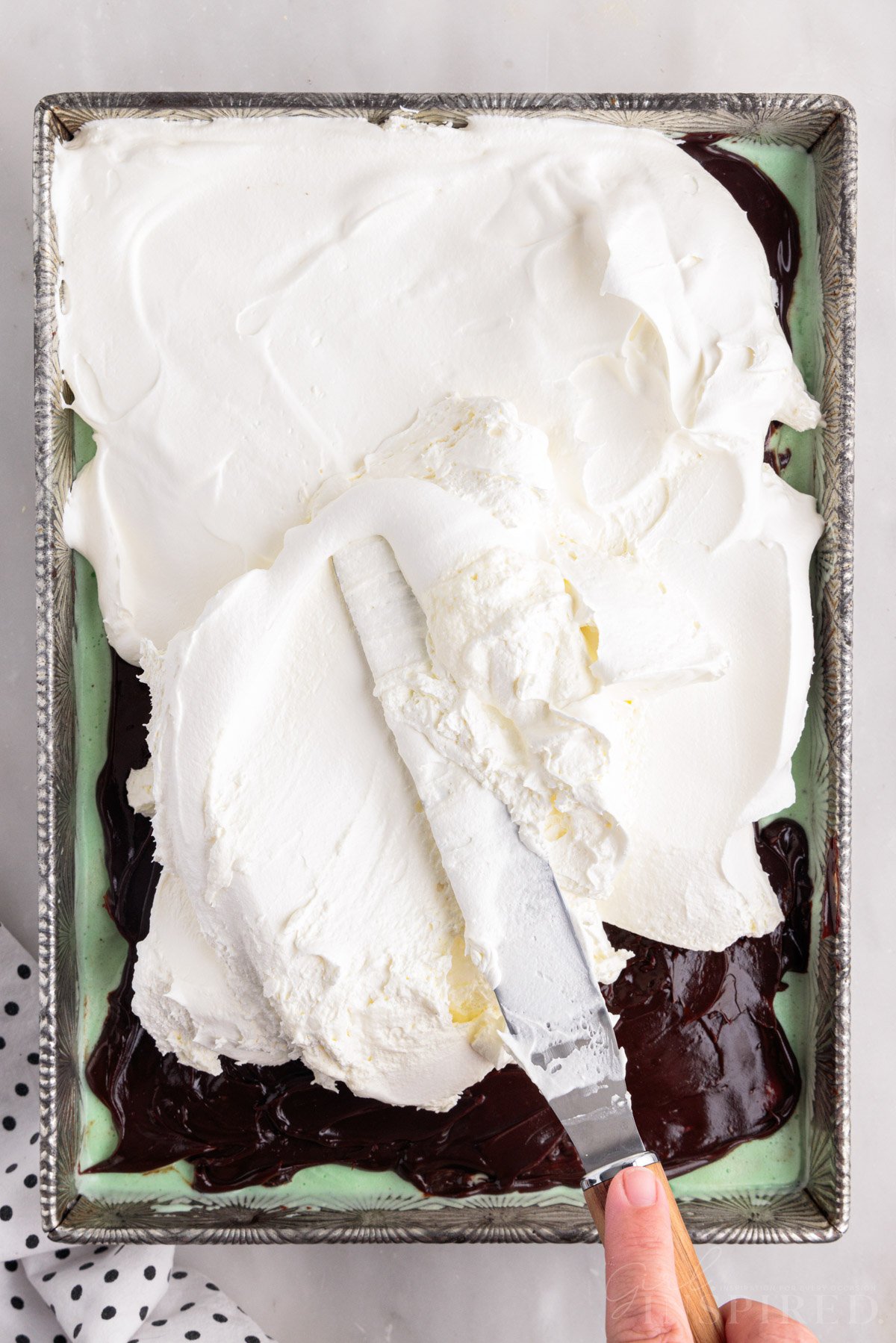 Cool whip spread onto hot fudge layer with offset spatula.
