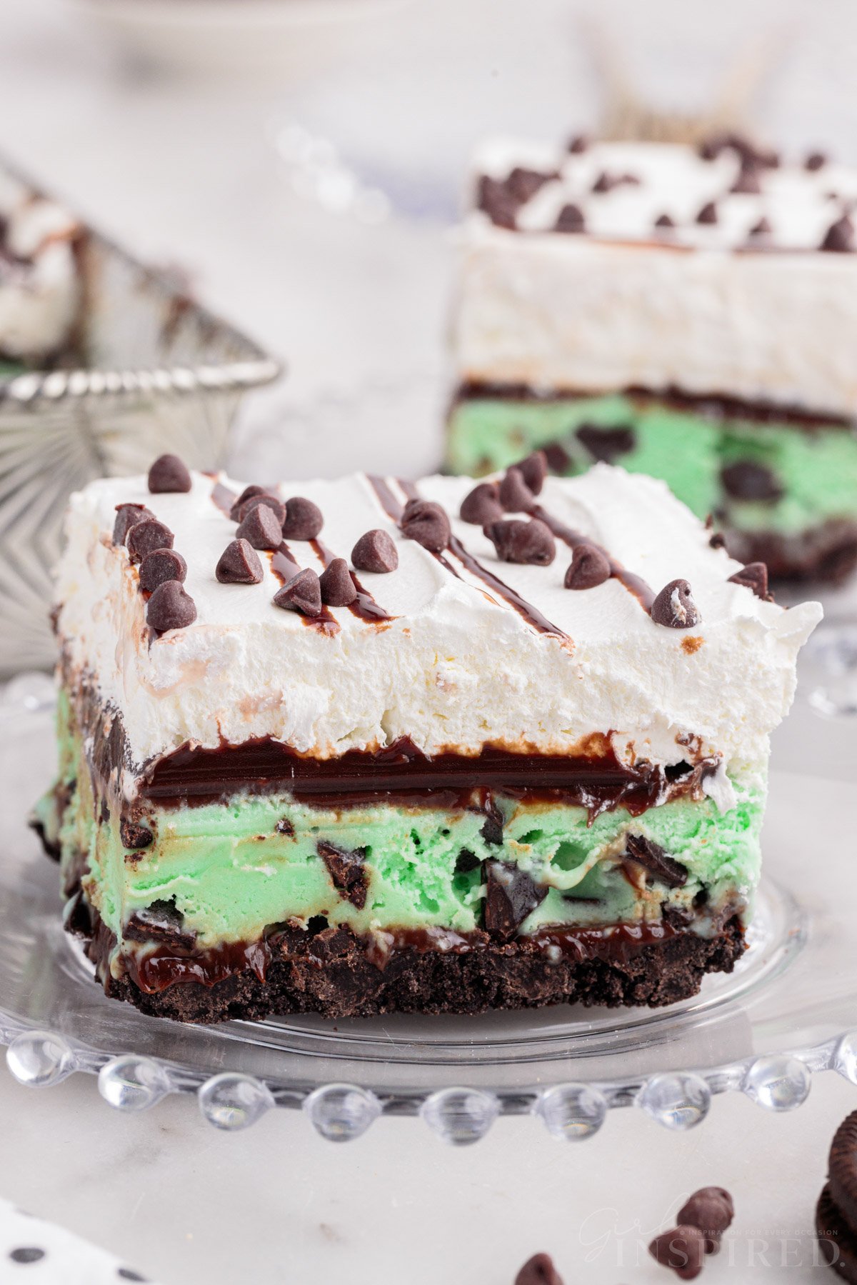 Slice of mint chocolate chip ice cream cake on a glass plate.