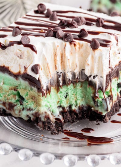 Slice of mint chocolate chip ice cream cake with bite taken out on a glass plate.