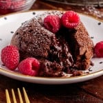 Close up of a Molten Lava Cake sliced open with raspberries on top.