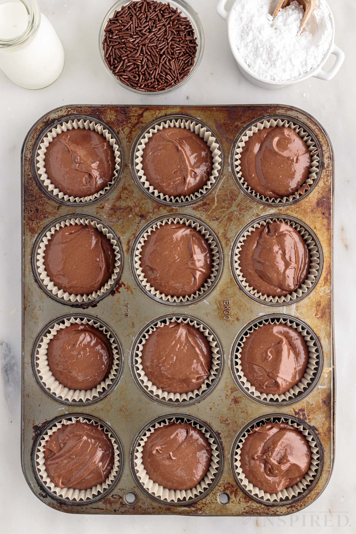 A cupcake pan with liners filled with Nutella Cupcake batter.