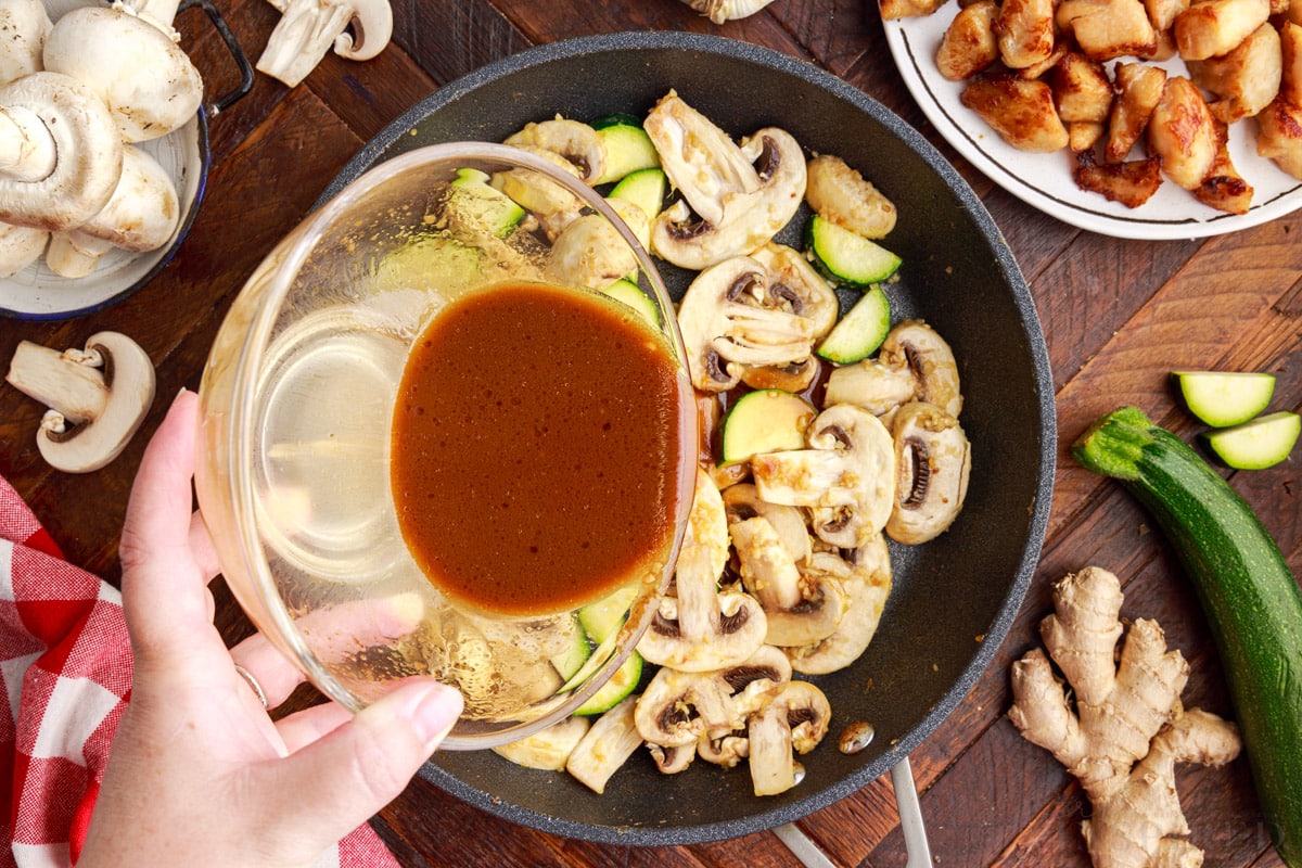 Sauce mixture poured on top of veggies in skillet to make panda express mushroom chicken.