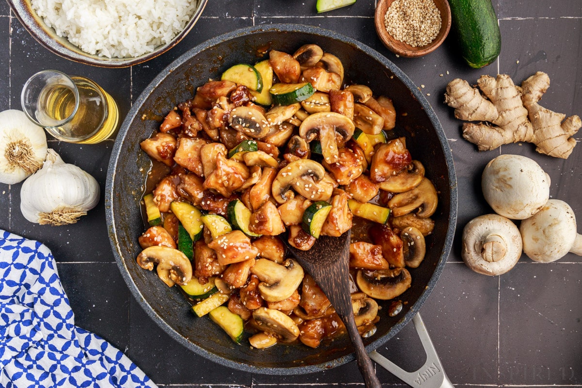 Top view of panda express mushroom chicken in skillet surrounded by additional ingredients for panda express mushroom chicken.