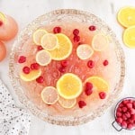 Overhead view of party punch in a glass punch bowl with fresh raspberries and citrus slices floating in the bowl.