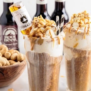 Zoomed view of two peanut butter root beer whiskey floats with a mini bottle of Skrewball whiskey inserted in the one glass.