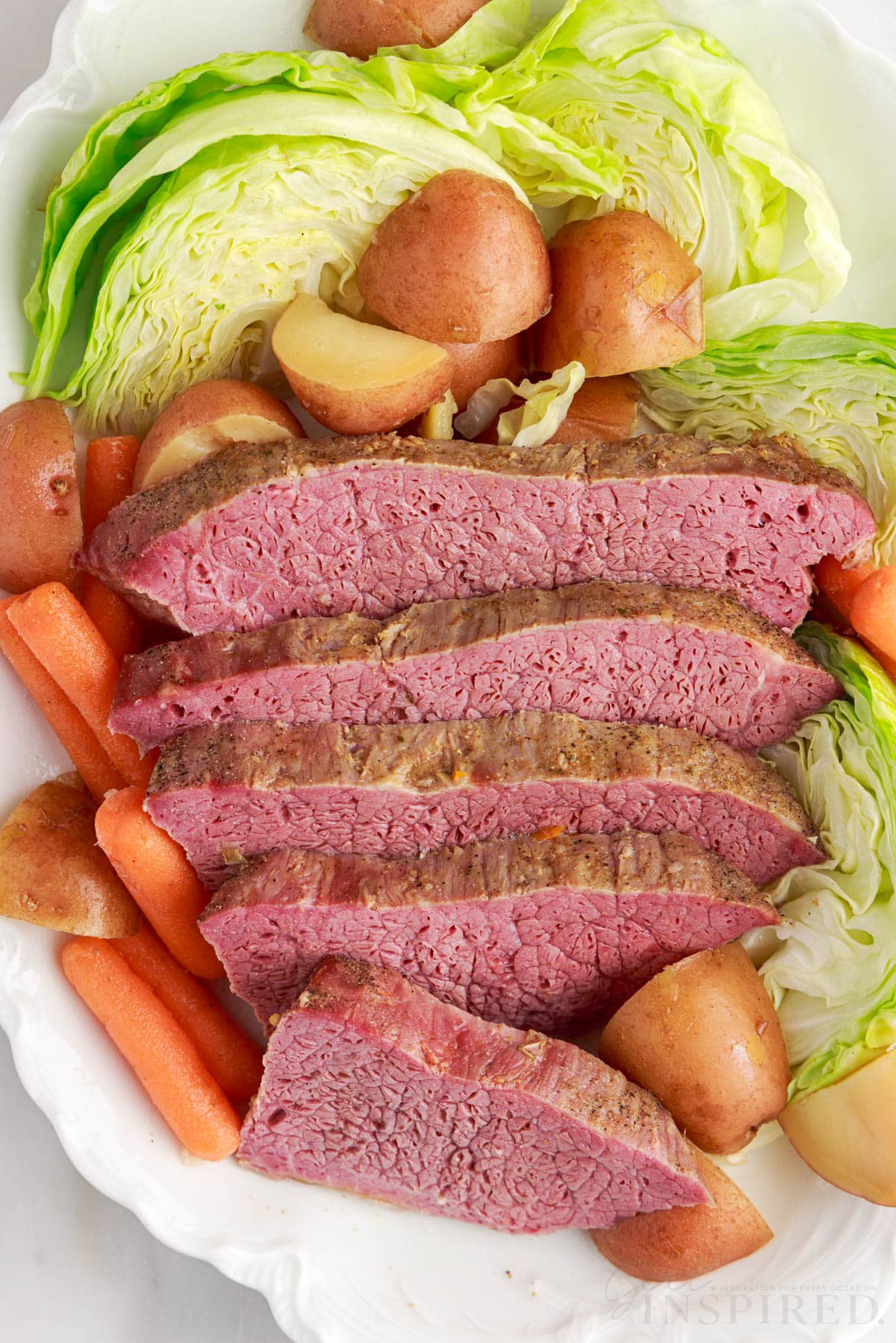 corned beef cut into slices on plate with cabbage carrots and potatoes