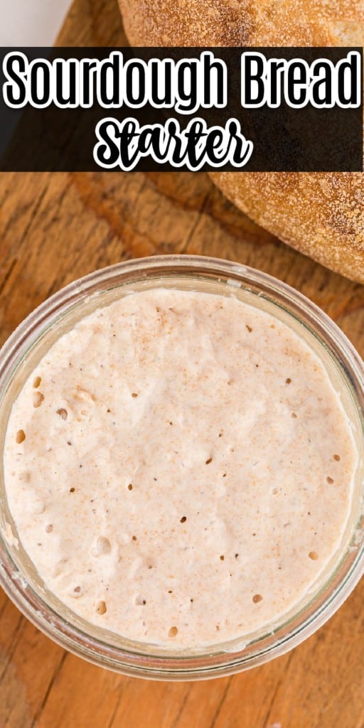 sourdough bread starter in a glass bowl on top of a wooden board with a loaf of bread on the side