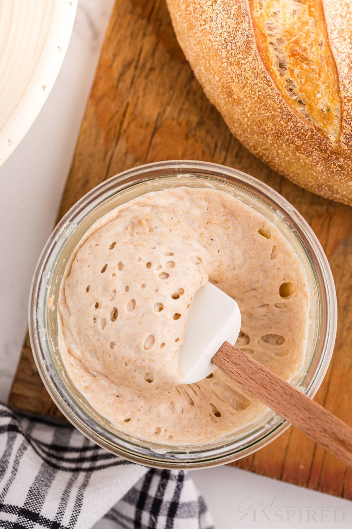 bubbly sourdough starter in a glass bowl with spatula.