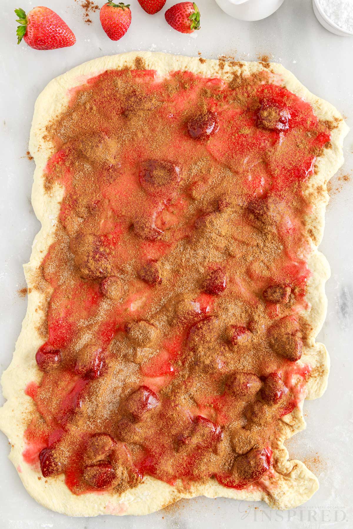 Cinnamon and sugar layered over strawberry pie filling on top of dough.