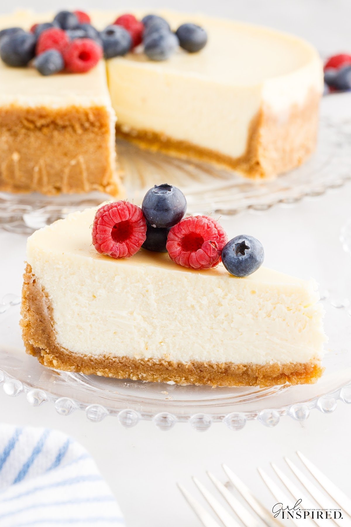 Slice of Cheesecake with graham cracker crust on a plate with berries on top.