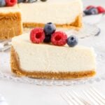 Slice of Classic Cheesecake with graham cracker crust with berries on top.