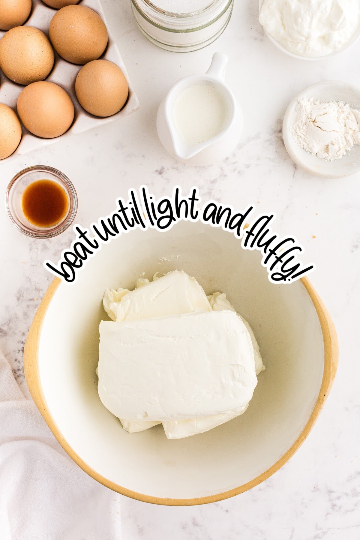 Large bowl with cream cheese blocks and text overlay "beat until light and fluffy."