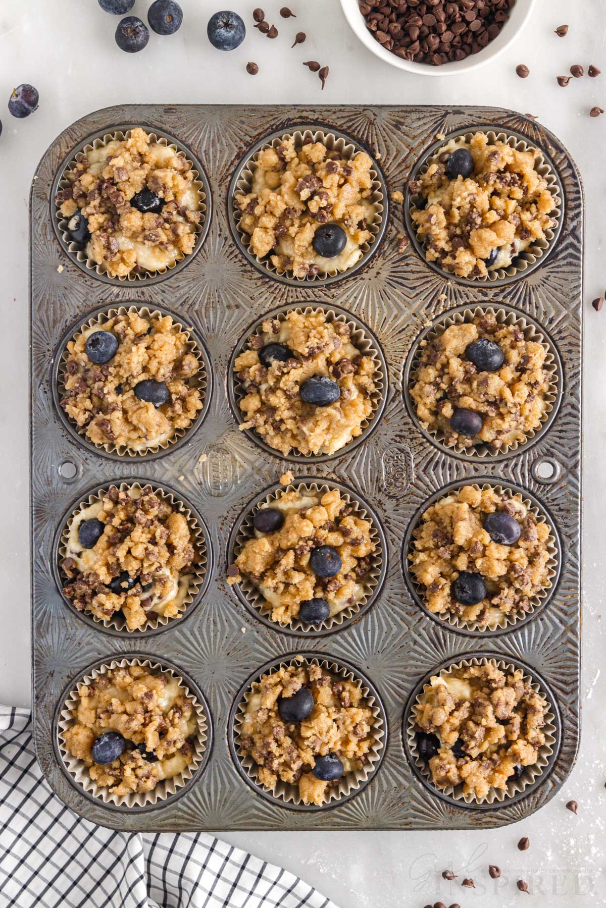 Streusel and blueberries added to the tops of the muffin batter in the muffin tin.