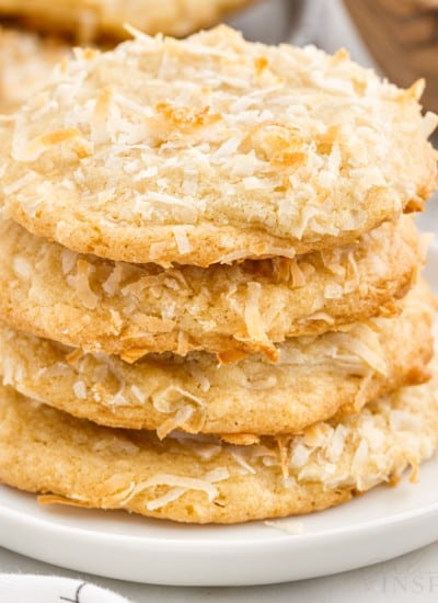 Four Chewy Coconut Cookies stacked on each other on a small plate.